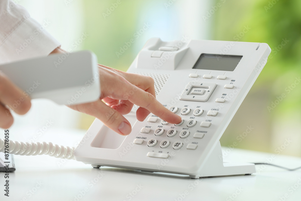 Assistant dialing number on telephone against blurred background, closeup Assistant dialing number on telephone against blurred background, closeup