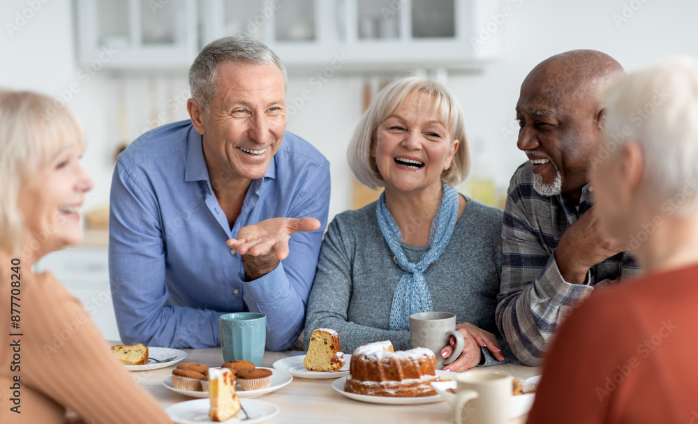 © Prostock-studio - Multiracial group of happy senior people sitting around table drinking tea with cake and having conversation, smiling and laughing, having home party or enjoying time at nursing home