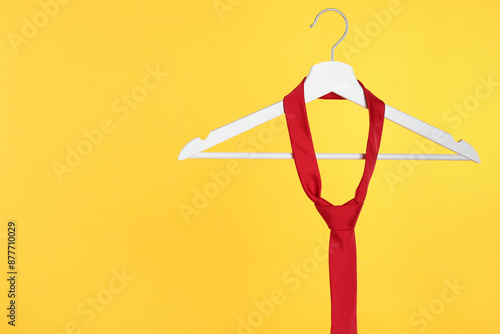 Hanger with red tie against orange background. Space for text