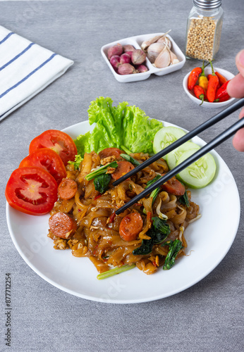 Kwetiaw or Kwetiau, fried rice noodles with sausage, egg and vegetables. Perfect for recipe, article, catalogue, promotion, or any cooking contents. photo