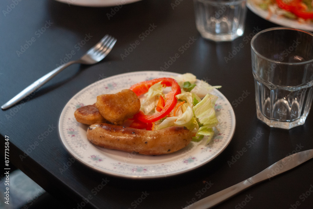 dinner table with chicken nuggets, sausages, fries and salad. dinner table with chicken nuggets, sausages, fries and salad.