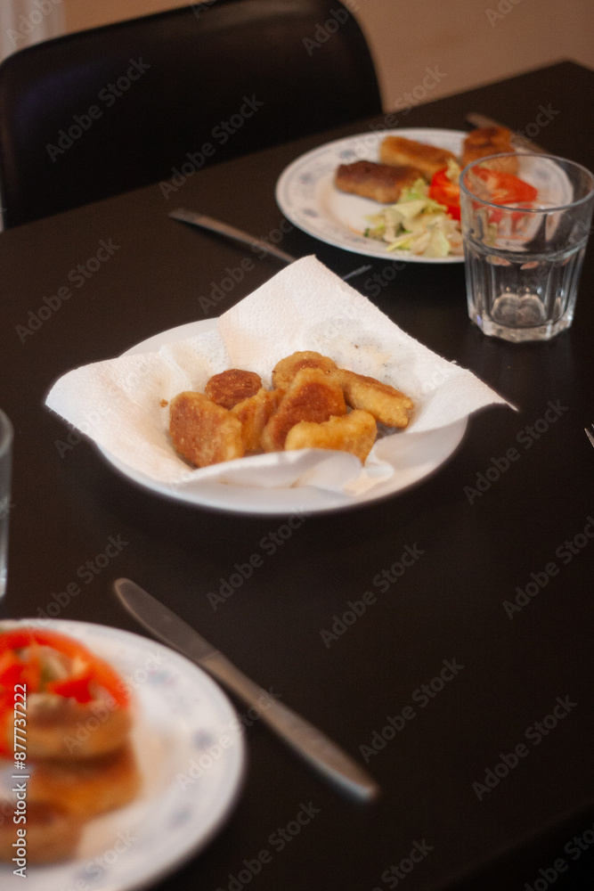 dinner table with chicken nuggets, sausages, fries and salad. dinner table with chicken nuggets, sausages, fries and salad.