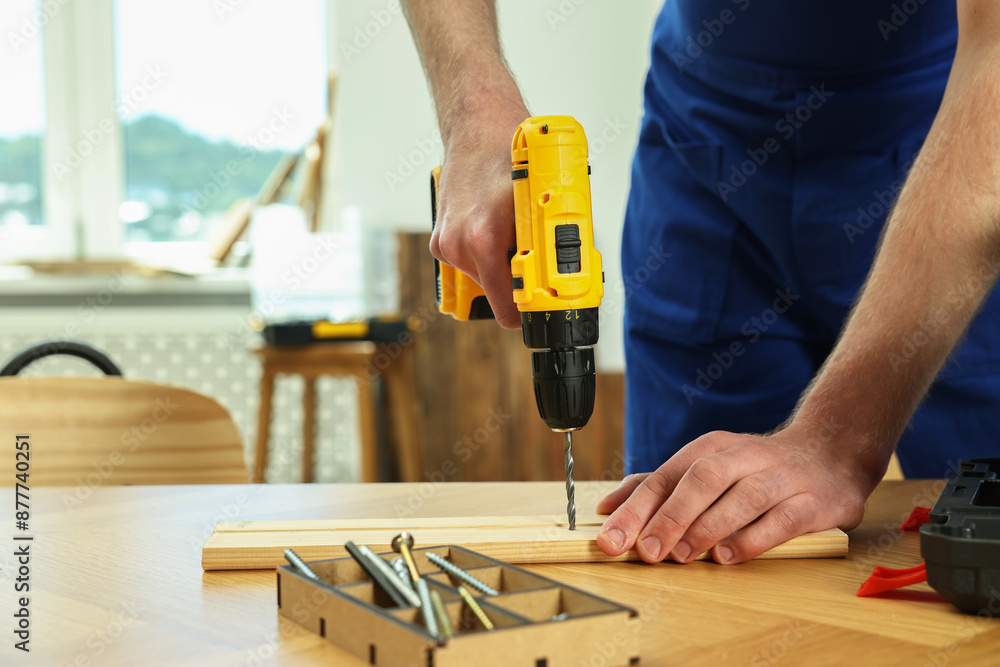 Craftsman working with drill at wooden table in workshop, closeup Craftsman working with drill at wooden table in workshop, closeup