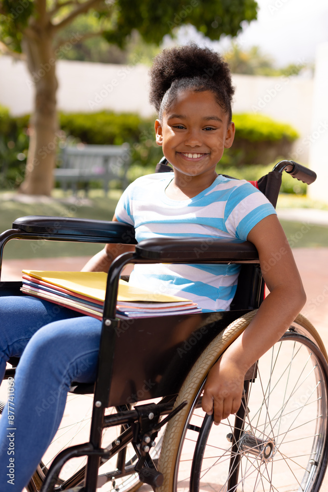 Obraz premium Portrait of happy african american schoolgirl in wheelchair at school
