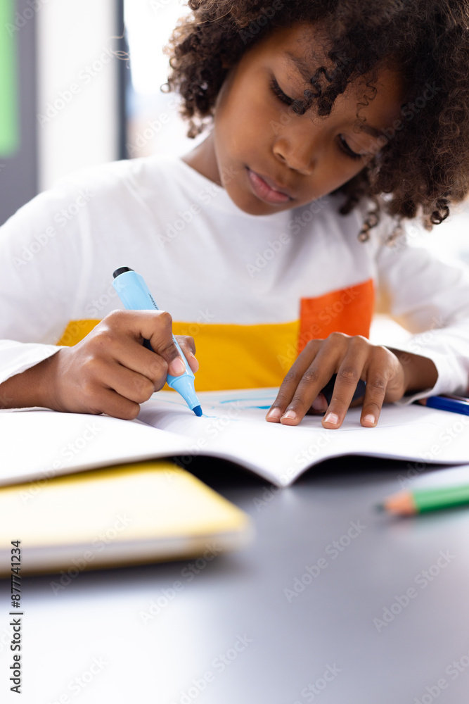 Happy african american schoolboy sitting at desk in school classroom Happy african american schoolboy sitting at desk in school classroom