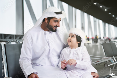 Middle East family travelling together at airport. Arab father and son wearing kandora dishdash while waiting for their flight.