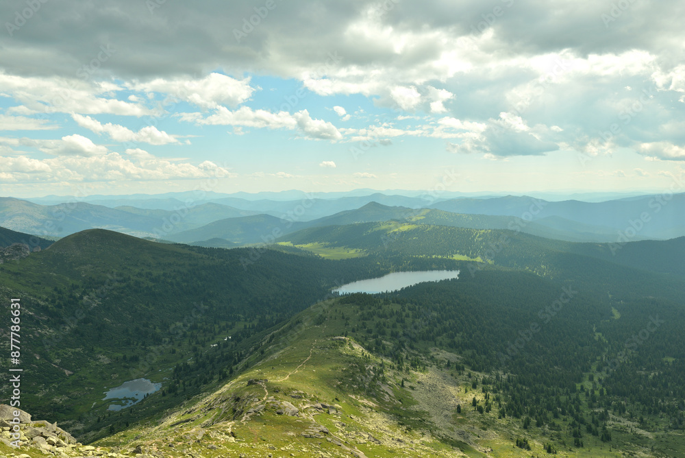 Fototapeta premium A picturesque valley sandwiched in the mountains and two picturesque lakes separated by a mountain range on a cloudy summer day.