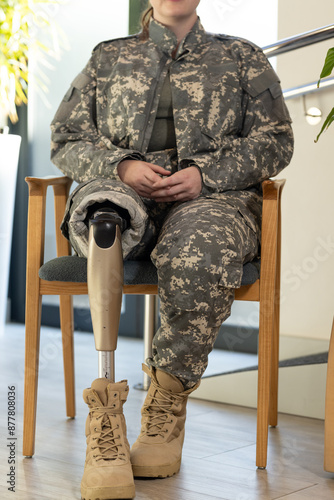 Military soldier personnel with prosthetic leg sitting on chair, wearing camouflage uniform photo