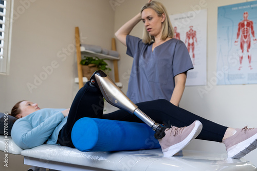 Physical therapist assisting woman with prosthetic leg during rehabilitation session photo