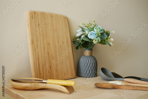 Wooden Cutting Board with Cooking Utensils and Vase of Flowers on Kitchen Counter photo