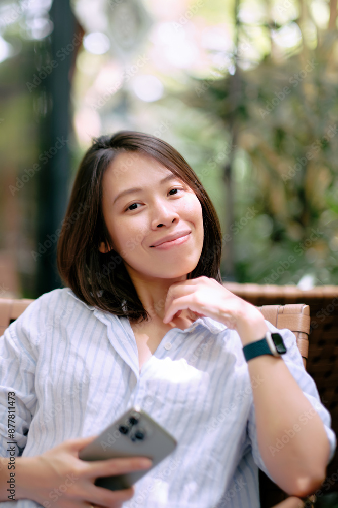A cheerful young Asian woman sitting in a coffee shop or cafe. A cheerful young Asian woman sitting in a coffee shop or cafe.