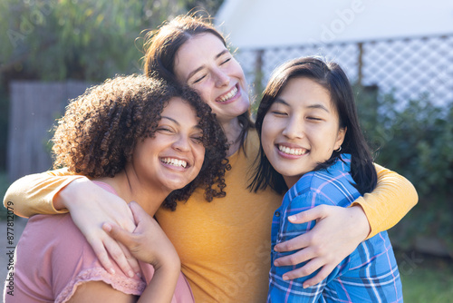 Smiling and hugging, three women friends enjoying time together outdoors