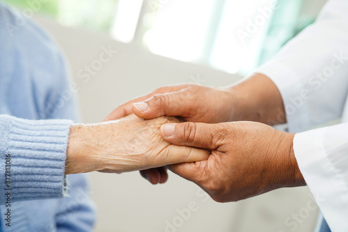 Doctor holding hand and help senior woman patient in hospital.