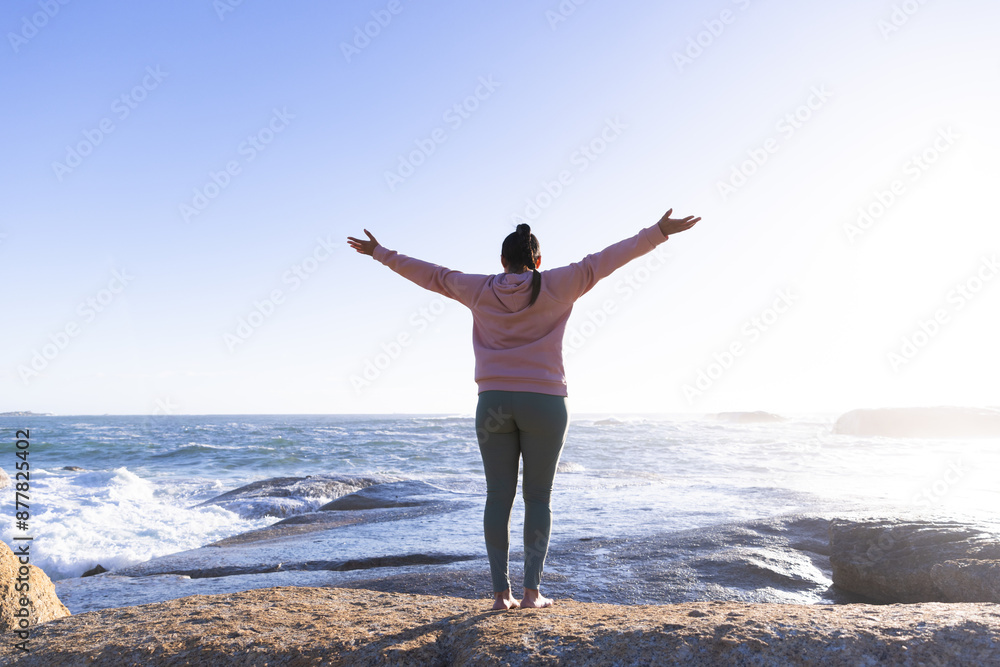 Standing on rocks by ocean, woman stretching arms and enjoying nature, copy space Standing on rocks by ocean, woman stretching arms and enjoying nature, copy space