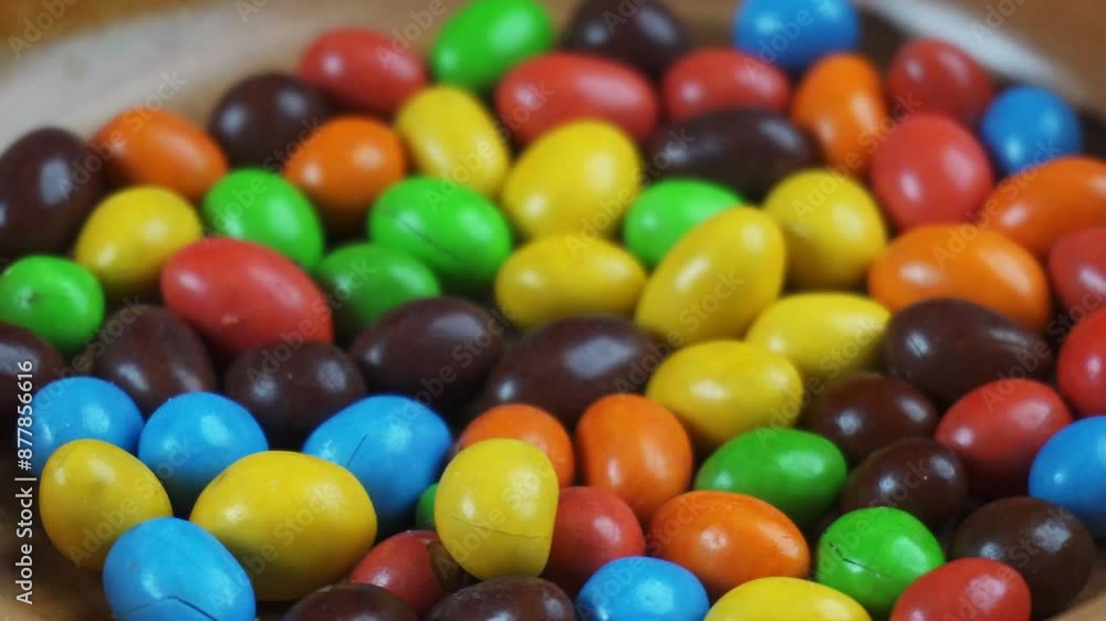 close up of rainbow peanut chocolate candies in spinning wooden bowl close up of rainbow peanut chocolate candies in spinning wooden bowl