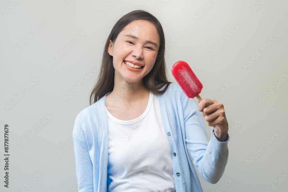 Cheerful, happy positive asian woman wearing casual with brunette hair, enjoy eating delicious popsicle, girl holding cold dessert, frozen stick with strawberry ice cream tasty isolated on background. Cheerful, happy positive asian woman wearing casual with brunette hair, enjoy eating delicious popsicle, girl holding cold dessert, frozen stick with strawberry ice cream tasty isolated on background.