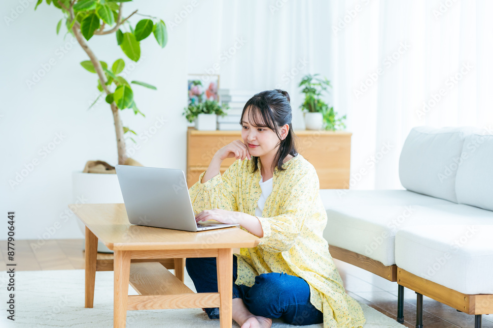 自宅でノートパソコンを操作する若い女性 自宅でノートパソコンを操作する若い女性