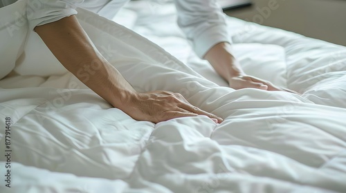 Changing Bed Sheets: Hands spreading fresh sheets over a mattress, making the bed.  © sarana