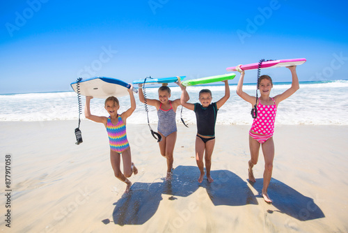 Photos Group of young girls carrying their boogie boards at the beach after playing in the scenic Pacific Ocean