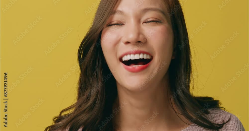 Happy young Asian woman showing cheerful and playful expression. Isolated on yellow background in studio Happy young Asian woman showing cheerful and playful expression. Isolated on yellow background in studio