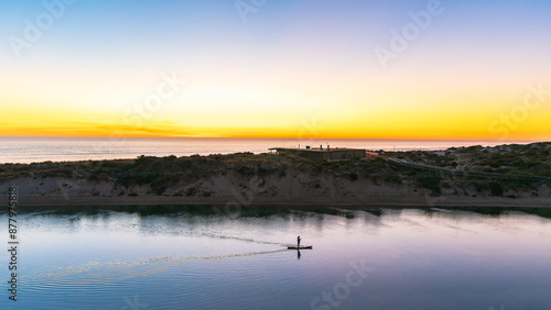 Silhouette of a man paddle boarding along the Onkaparinga River at dusk in South Australia