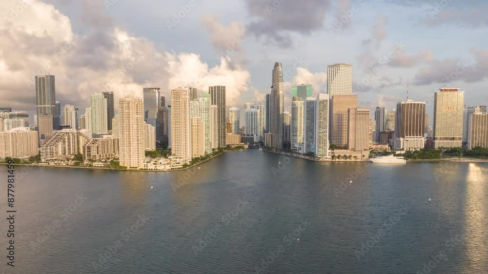 Morning sunrise aerial hyper lapse of Miami’s downtown skyline, featuring towering skyscrapers along the waterfront, with clear skies and reflections on the water. Morning sunrise aerial hyper lapse of Miami’s downtown skyline, featuring towering skyscrapers along the waterfront, with clear skies and reflections on the water.