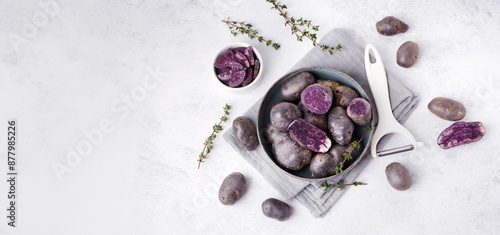 Konstfotografi Bowl of raw purple potatoes, thyme and peeler on light background with space for