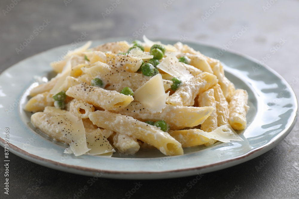 Delicious pasta with green peas, cheese and creamy sauce on grey table, closeup Delicious pasta with green peas, cheese and creamy sauce on grey table, closeup
