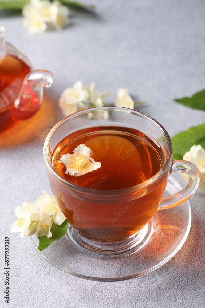 Hot jasmine tea in cup and flowers on light grey table Hot jasmine tea in cup and flowers on light grey table
