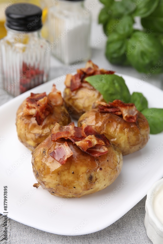 Delicious baked potatoes with bacon and basil on table, closeup Delicious baked potatoes with bacon and basil on table, closeup