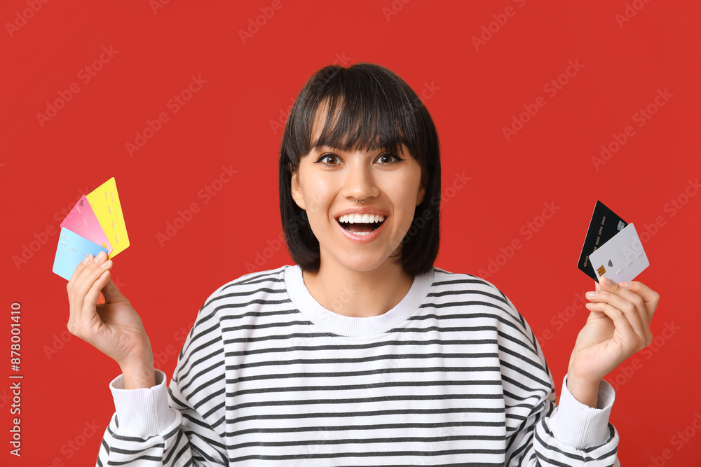 Beautiful young woman with many credit cards on red background Beautiful young woman with many credit cards on red background