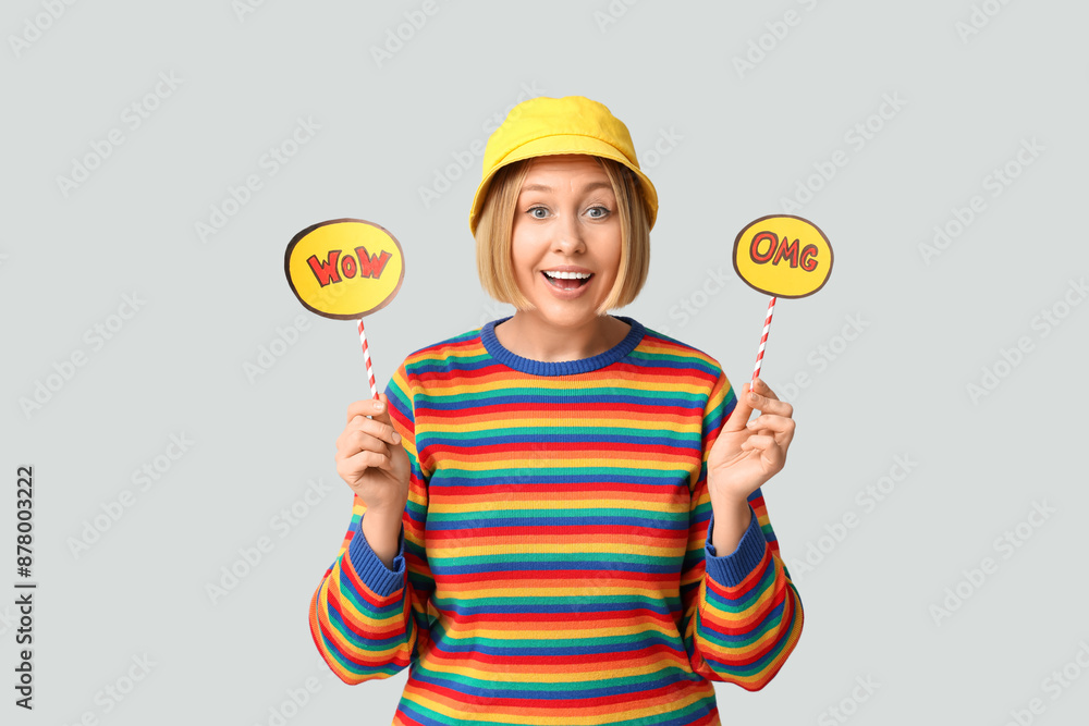 Surprised adult woman holding speech bubbles with words OMG and WOW on white background Surprised adult woman holding speech bubbles with words OMG and WOW on white background