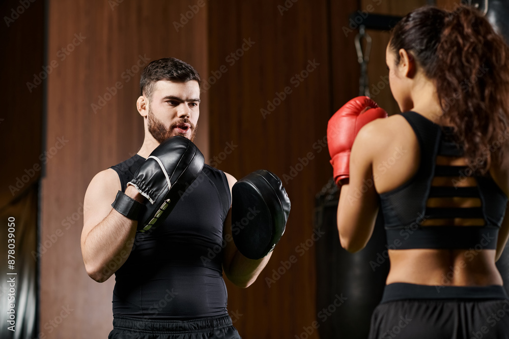 A male trainer guides a brunette sportswoman in active wear through a boxing session in a gym. A male trainer guides a brunette sportswoman in active wear through a boxing session in a gym.