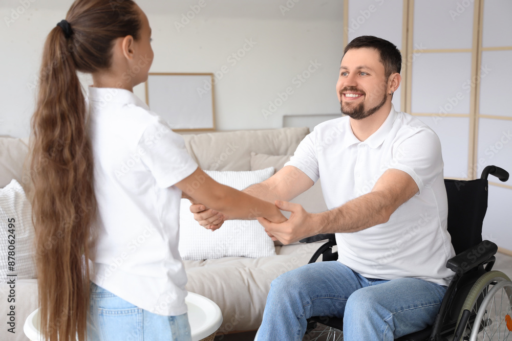 Little girl and her father in wheelchair holding hands at home Little girl and her father in wheelchair holding hands at home