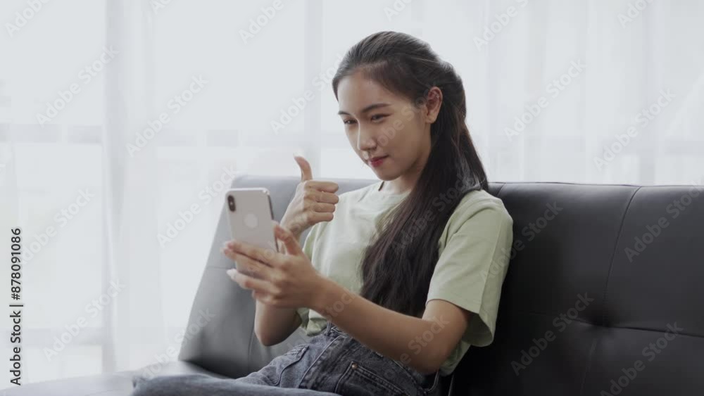 Young woman on sofa having an animated video call, showing excitement, happiness, and connection. She gestures enthusiastically, smiling and chatting with a smartphone Young woman on sofa having an animated video call, showing excitement, happiness, and connection. She gestures enthusiastically, smiling and chatting with a smartphone