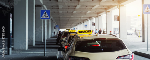 Taxi car Queue yellow taxi symbol  on roof stand waiting at parking of airport terminal or railway station Under Concrete Structure Transportation Hub. Urban street transportation comfort service