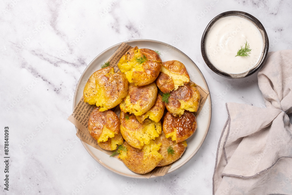 A plate of potato wedges sits on a marble countertop next to a bowl of dipping s A plate of potato wedges sits on a marble countertop next to a bowl of dipping s