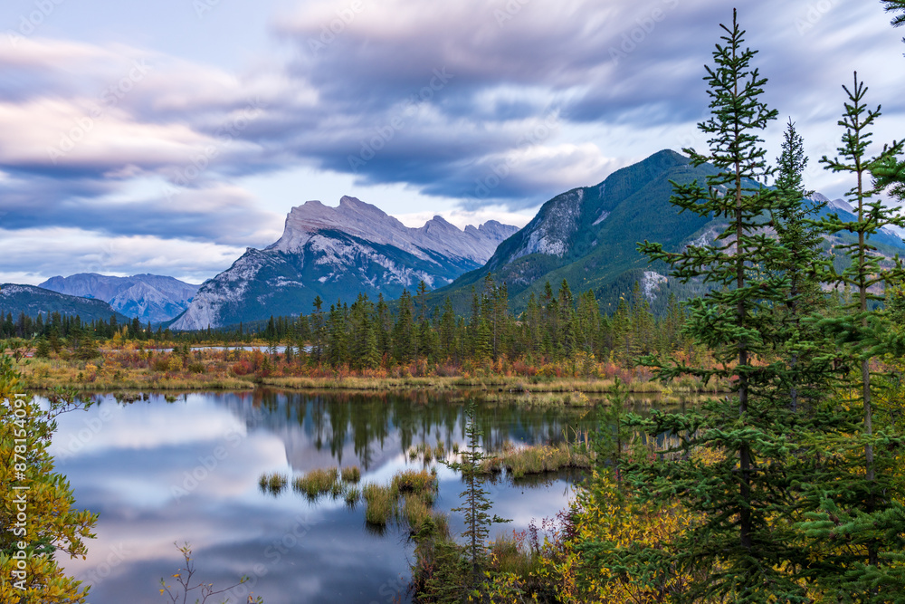 Vermilion Lakes autumn foliage scenery in dusk. Banff National Park, Canadian Rockies, Alberta, Canada. Colorful trees in orange, yellow, golden colors. Mount Rundle, Sulphur Mountain in background. Vermilion Lakes autumn foliage scenery in dusk. Banff National Park, Canadian Rockies, Alberta, Canada. Colorful trees in orange, yellow, golden colors. Mount Rundle, Sulphur Mountain in background.