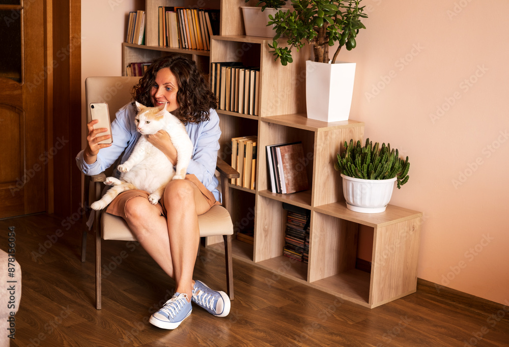 Woman sitting in chair and taking selfie with her cat. Woman sitting in chair and taking selfie with her cat.