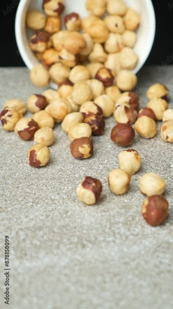 Scattering of peeled hazelnuts on a gray stone background, vertical slow motion Scattering of peeled hazelnuts on a gray stone background, vertical slow motion