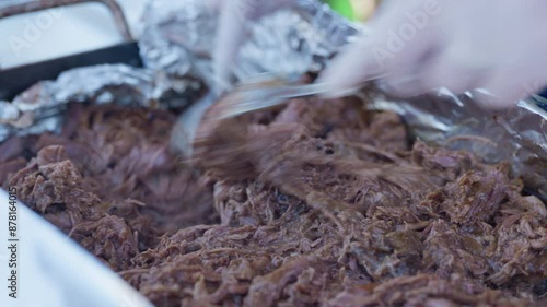 Close up, Beef brisket being shredded between two forks in a foil lined meat tray. photo