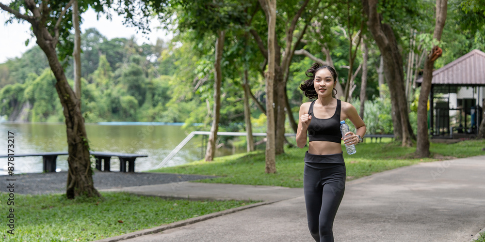 Young Woman Jogging in Park with Water Bottle, Enjoying Outdoor Exercise and Fresh Air Young Woman Jogging in Park with Water Bottle, Enjoying Outdoor Exercise and Fresh Air