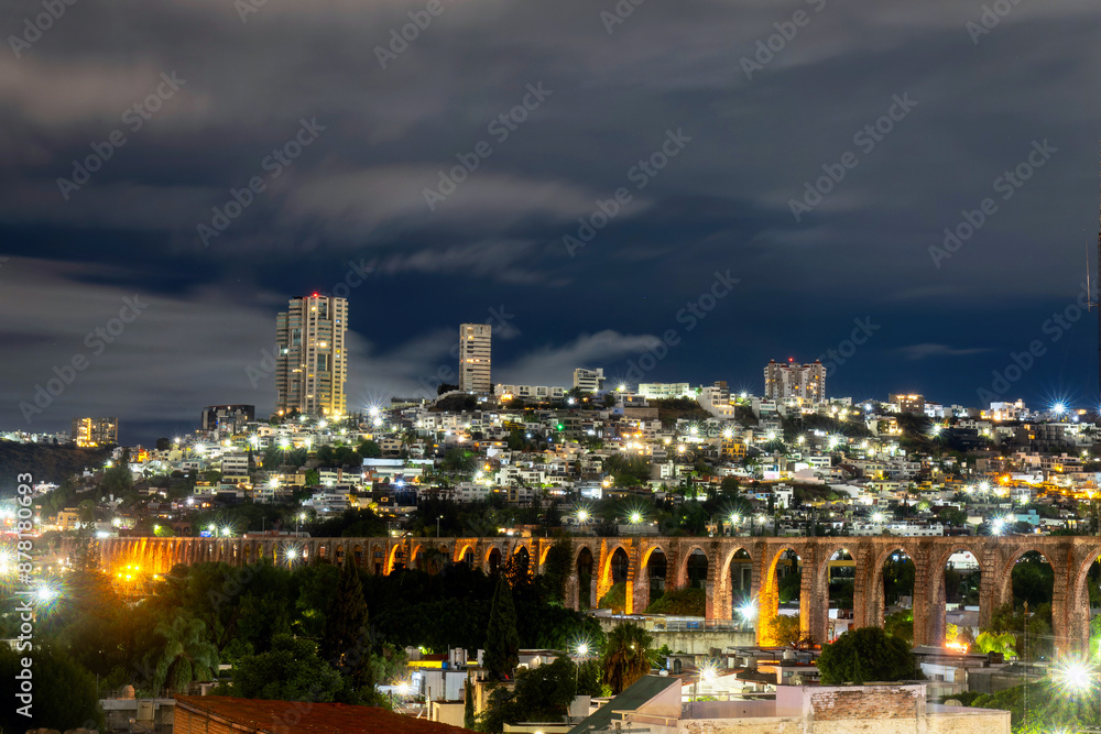 Fototapeta premium Night View of Illuminated Aqueduct of Queretaro Against a Modern Cityscape