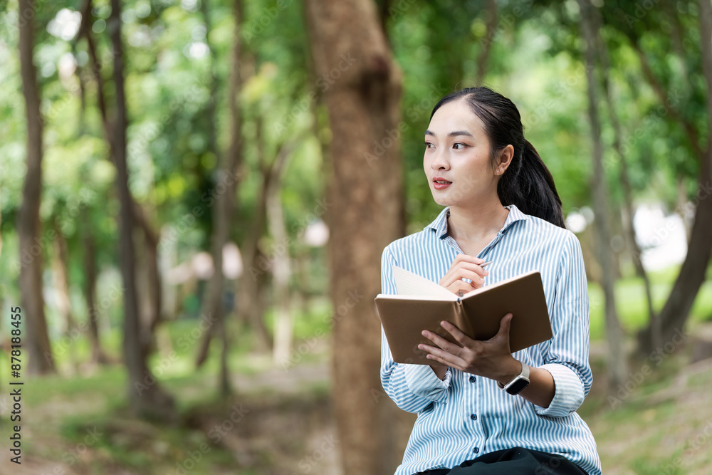 Young Digital Nomad Working Remotely in Nature, Holding Notebook and Pen, Reflecting on Ideas in a Serene Outdoor Setting Young Digital Nomad Working Remotely in Nature, Holding Notebook and Pen, Reflecting on Ideas in a Serene Outdoor Setting