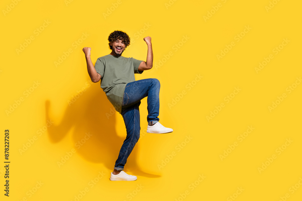 Full size photo of optimistic guy dressed khaki t-shirt jeans scream yeah raising fists up win bet isolated on yellow color background