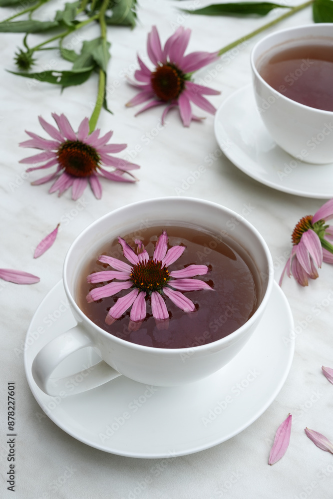 Herbal tea in white cups, fresh flowers of echinacea on a marble background. Side view. 