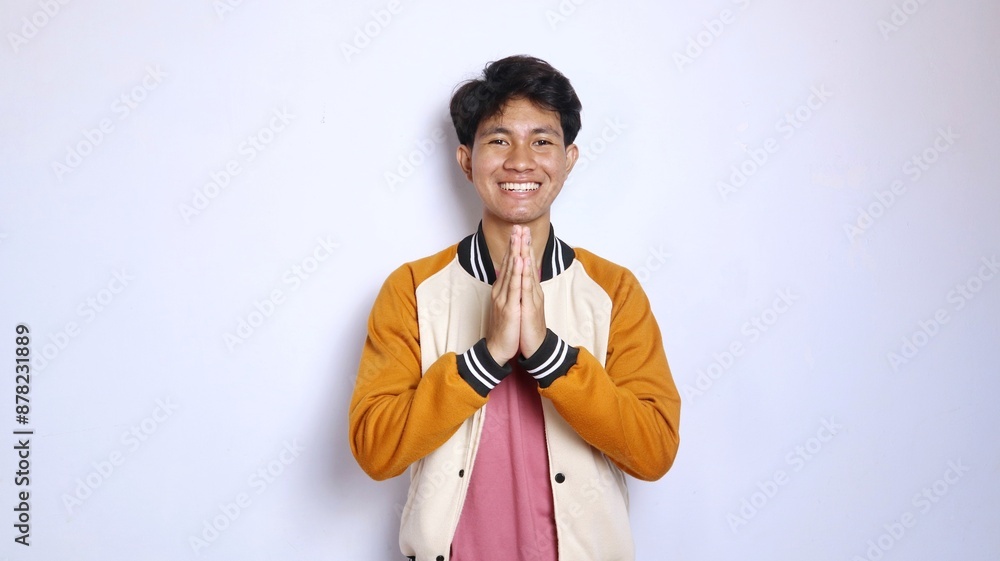 casual excited young handsome Asian man giving a greeting gesture casual excited young handsome Asian man giving a greeting gesture