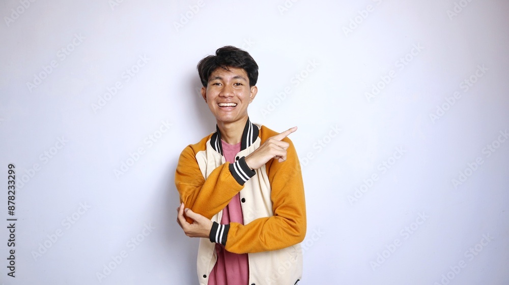 casual smiling young handsome asian man wearing jacket giving gesture pointing to the side casual smiling young handsome asian man wearing jacket giving gesture pointing to the side