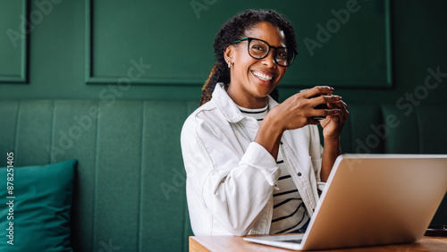 Happy black woman smiling while working on her laptop