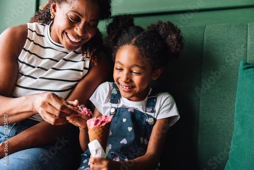 Happy black mother and daughter enjoying ice cream together photo